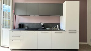 A modern kitchen with grey cabinets, a black countertop, and a built-in oven. - Domo House 3 (Domodossola)