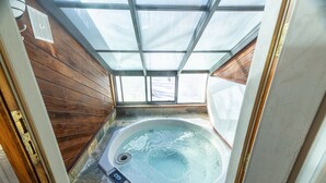 Ein Whirlpool mit Glasdecke, Holzverkleidung und Steinböden.