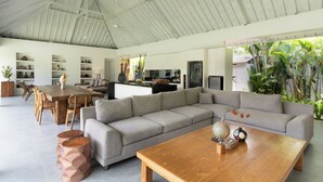 Ein großzügiger Wohnbereich mit einem großen Holzesstisch, einem grauen Ecksofa und einem Couchtisch aus Holz.