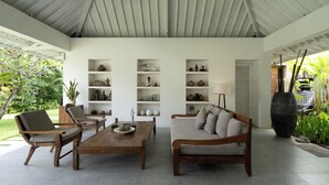 Ein modernes Wohnzimmer mit einem Holztisch, zwei Sofas und einem Bücherregal voller dekorativer Gegenstände.
