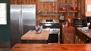 Eine rustikale Küche mit Holzwänden, einem Edelstahlkühlschrank, einem Holztisch und einem Schild mit der Aufschrift 'gather'.