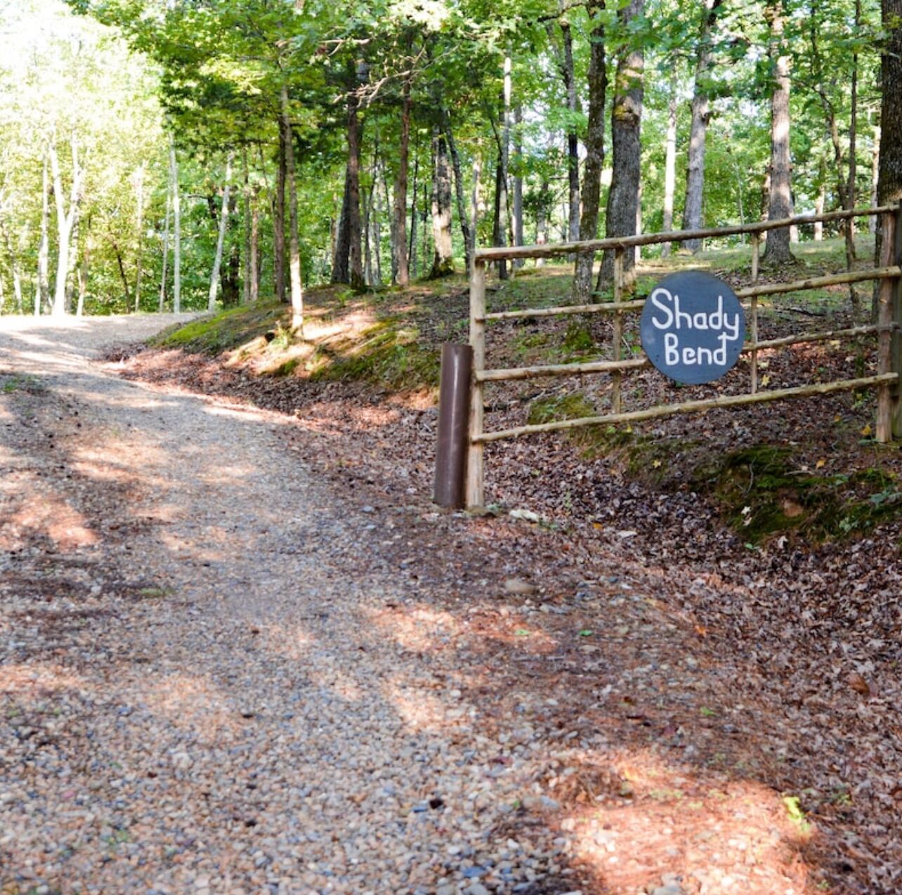A gravel path leading to a wooden gate with a sign that reads "Shady Bend."