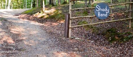 A gravel path leading to a wooden gate with a sign that reads "Shady Bend."