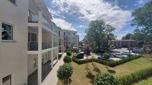 Ein mehrgeschossiges Wohnhaus mit Balkonen, einem Parkplatz und einem gepflegten Rasen.