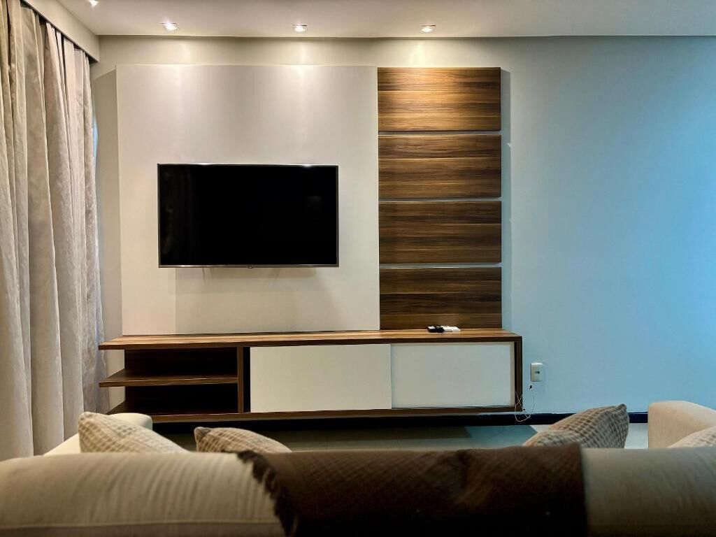 Una sala de estar moderna con un televisor de pantalla plana montado en la pared, una pared de acento de madera y un mueble empotrado para entretenimiento.