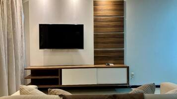 Una sala de estar moderna con un televisor de pantalla plana montado en la pared, una pared de acento de madera y un mueble empotrado para entretenimiento.