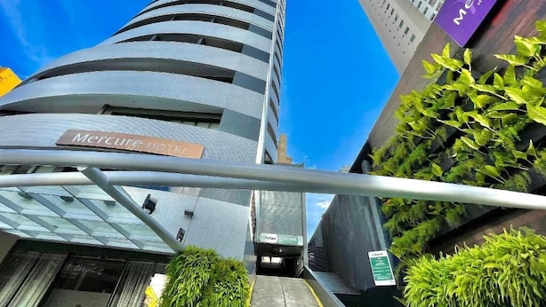 Das äußere Erscheinungsbild des Mercure Hotels mit modernem Design, blauem Himmel und umgebender Bepflanzung.
