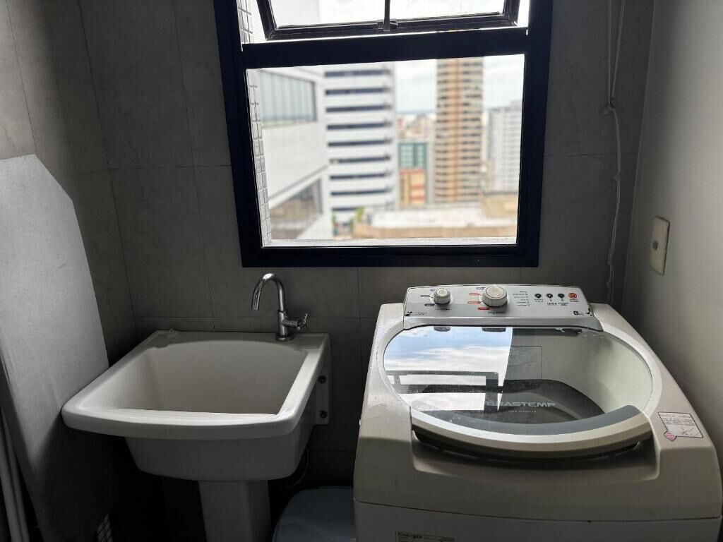 Un baño pequeño con lavabo y lavadora de carga frontal.