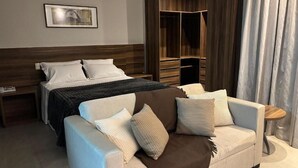 Ein Schlafzimmer mit einem Bett, einer Schlafcouch, einem Holzschrank und einem Nachttisch.
