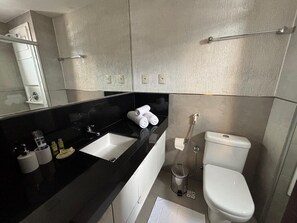 A modern bathroom with a black countertop, a white sink, a toilet, and a shower. - Flats no Hotel Mercure Belém Boulevard (Belém)