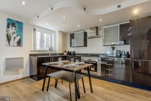 Et moderne køkken med spiseplads, rustfrit stål hvidevarer og et stort vindue.