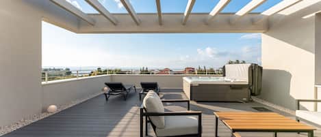 A rooftop terrace with a clear view of the city skyline, a hot tub, and lounge seating.
