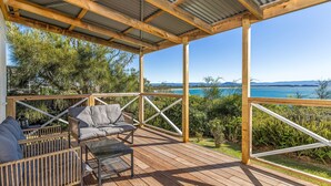 A wooden deck with outdoor furniture, a metal roof, and a view of the sea. - Moon Gate at Culburra - Pet Friendly Absolute Beachfront (Culburra Beach)