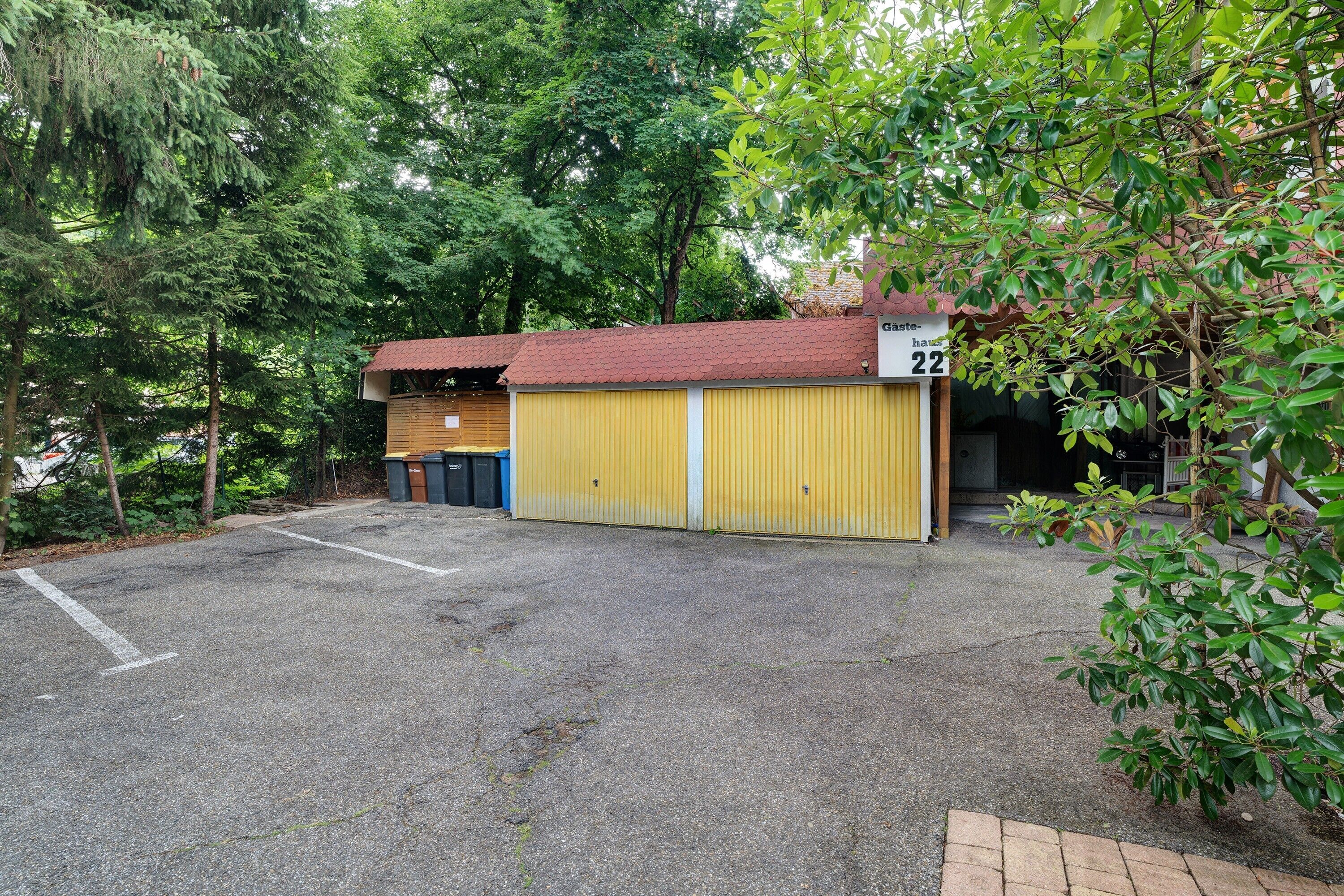 A yellow building with a red roof, marked with the number 22, surrounded by trees.