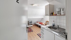 Eine kompakte Küche mit Einbau-Mikrowelle, Kaffeemaschine und Spüle.