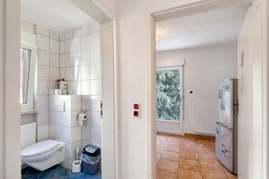 A bathroom with a toilet, a trash bin, and a window. - Apartment '4' with Shared Terrace and Wi-Fi (Baden-Baden)