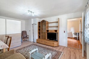 A living room with a TV, wooden entertainment unit, a dining area, and a separate seating area. - Apartment '4' with Shared Terrace and Wi-Fi (Baden-Baden)