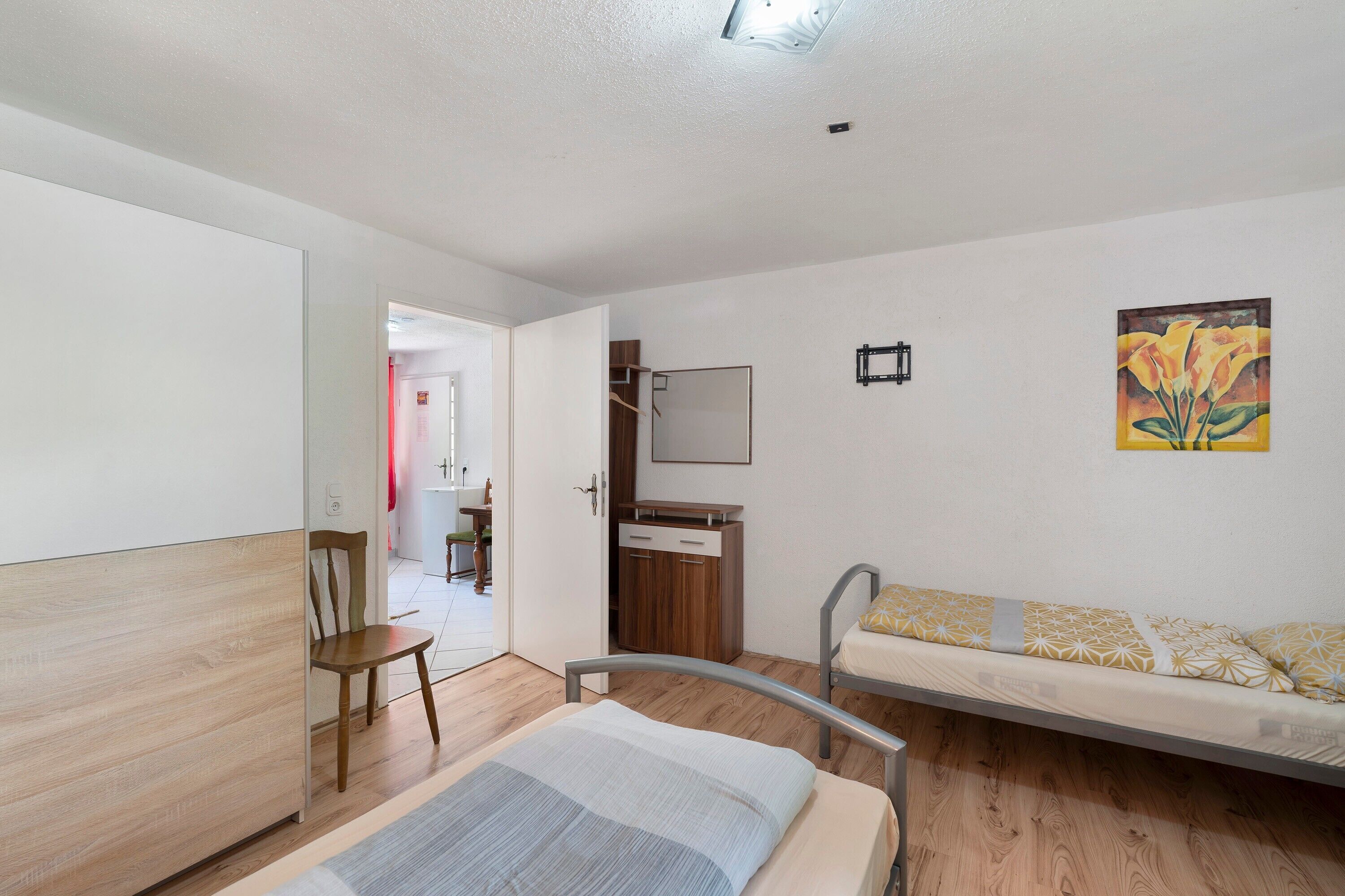 Une chambre à coucher avec un lit, une chaise en bois, un canapé, une armoire et un tableau accroché au mur.