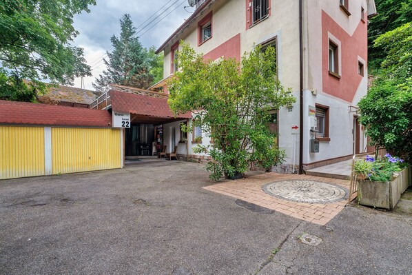 A building with a yellow garage door, a small tree in the front yard, and a paved entrance area.