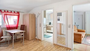 A room with a dining table, chairs, a wardrobe, a mirror, a sofa, and a kitchen area visible through an open door. - Room '3' with Shared Terrace and Wi-Fi (Baden-Baden)