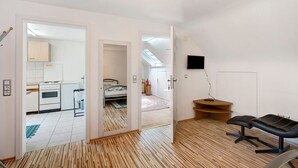 A modern apartment with a kitchen, a bedroom, a living area with a black office chair, and a TV mounted on the wall. - Room '3' with Shared Terrace and Wi-Fi (Baden-Baden)