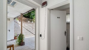 A hallway with a white door labeled 'BAD,' a potted plant, a wooden bench, and a staircase leading outside. - Room 7 with Shared Terrace and Wi-Fi (Baden-Baden)
