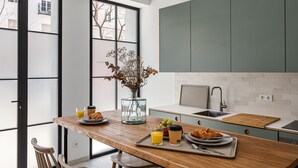Een moderne keuken met een houten tafel, een ontbijttafel en een vaas met gedroogde bloemen.