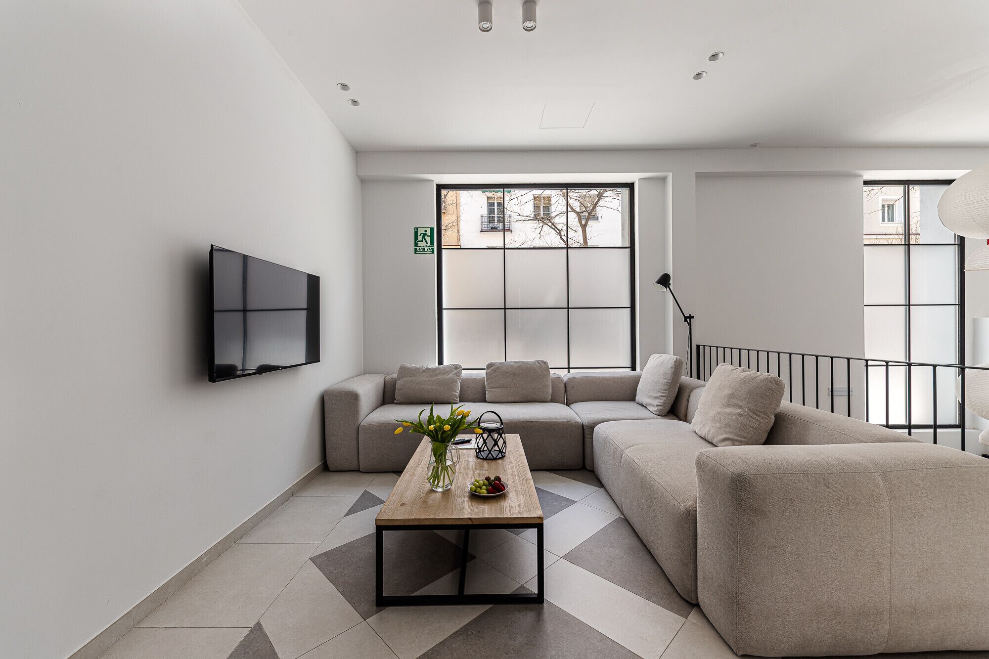 Una sala de estar moderna con un sofá modular, una mesa de centro y un televisor de pantalla plana montado en la pared.