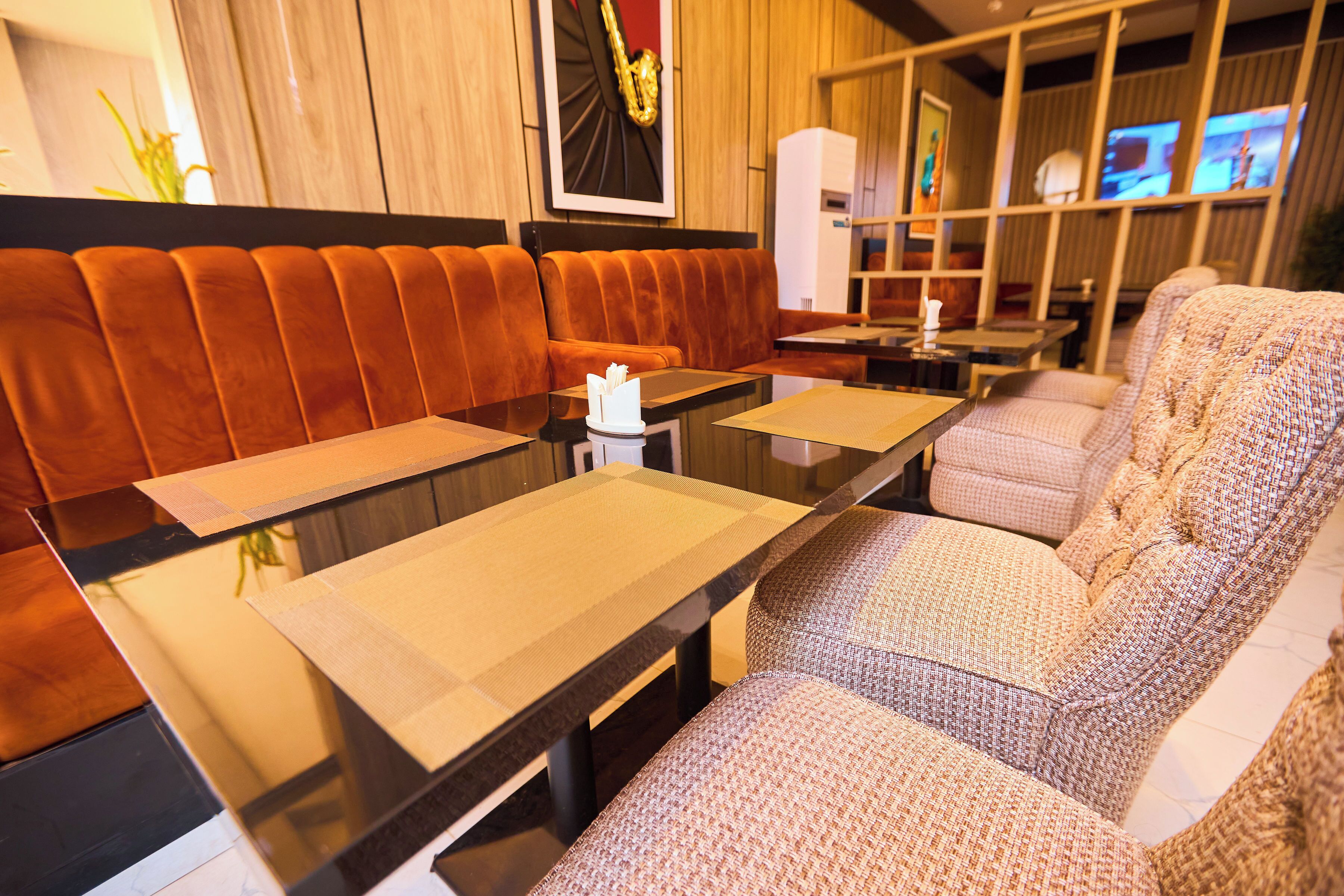Een restaurant met een lange tafel, zachte zittingen en een aan de muur bevestigde televisie.