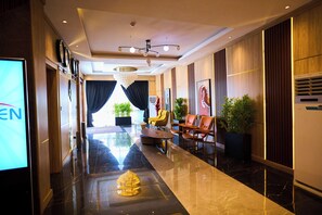 A hotel lobby with a marble floor, a chandelier, seating area, and a large screen displaying 'EN'. - Bourdillon Hotel & Apartments Airport Rd (Abuja)