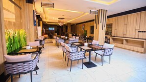 A modern restaurant with a long counter, cushioned chairs, and a clean, tiled floor. - Bourdillon Hotel & Apartments Airport Rd (Abuja)
