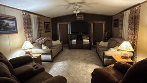 A living room with two sofas, a coffee table, a TV, and a ceiling fan. - Lake Oahe Retreat (Pierre)