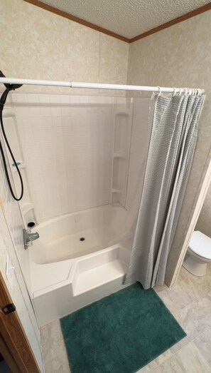 A bathroom with a shower, a bathtub, and a toilet.