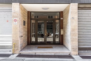 A building entrance with a glass door, a metal gate, and a no parking sign. - Casa Garbo by Wonderful Italy (Bologna)