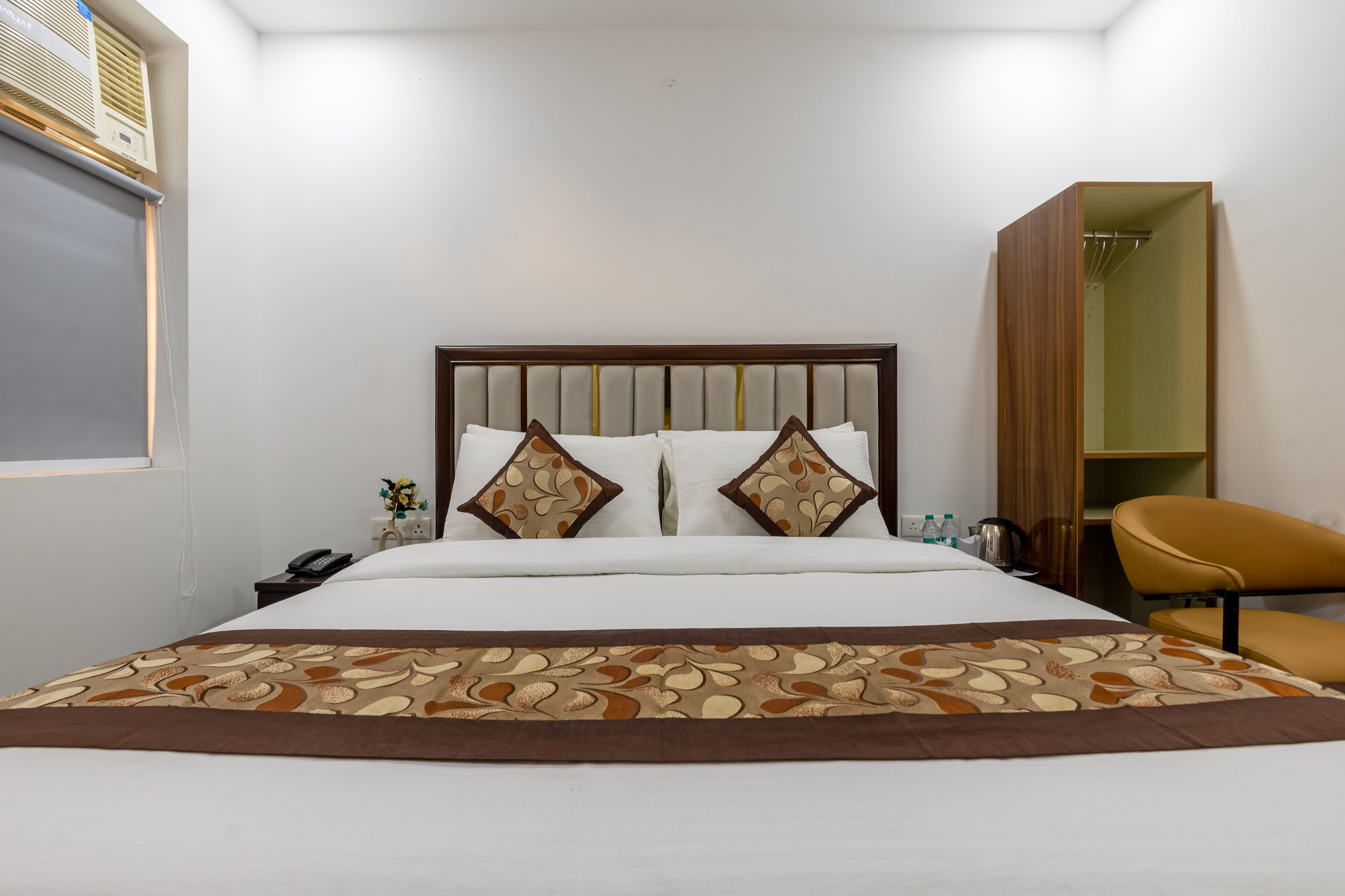 A hotel room with a bed, bedside table, lamp, and a wardrobe.