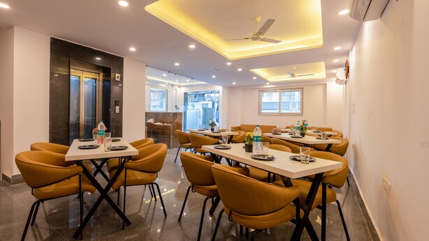 A modern conference room with tables and chairs, an elevator, and a ceiling fan. - Hotel park Tree I Sec-63a I Noida (Noida)