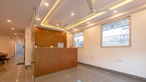 A modern reception area with a wooden reception desk, a large window, and a ceiling fan. - Hotel park Tree I Sec-63a I Noida (Noida)