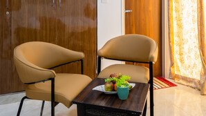 A room with a wooden wardrobe, a wooden door, a table with a fruit bowl, and a chair. - Hotel park Tree I Sec-63a I Noida (Noida)