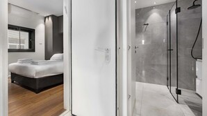 Een moderne slaapkamer met een bed, nachtkastje en een raam met jaloezieën.