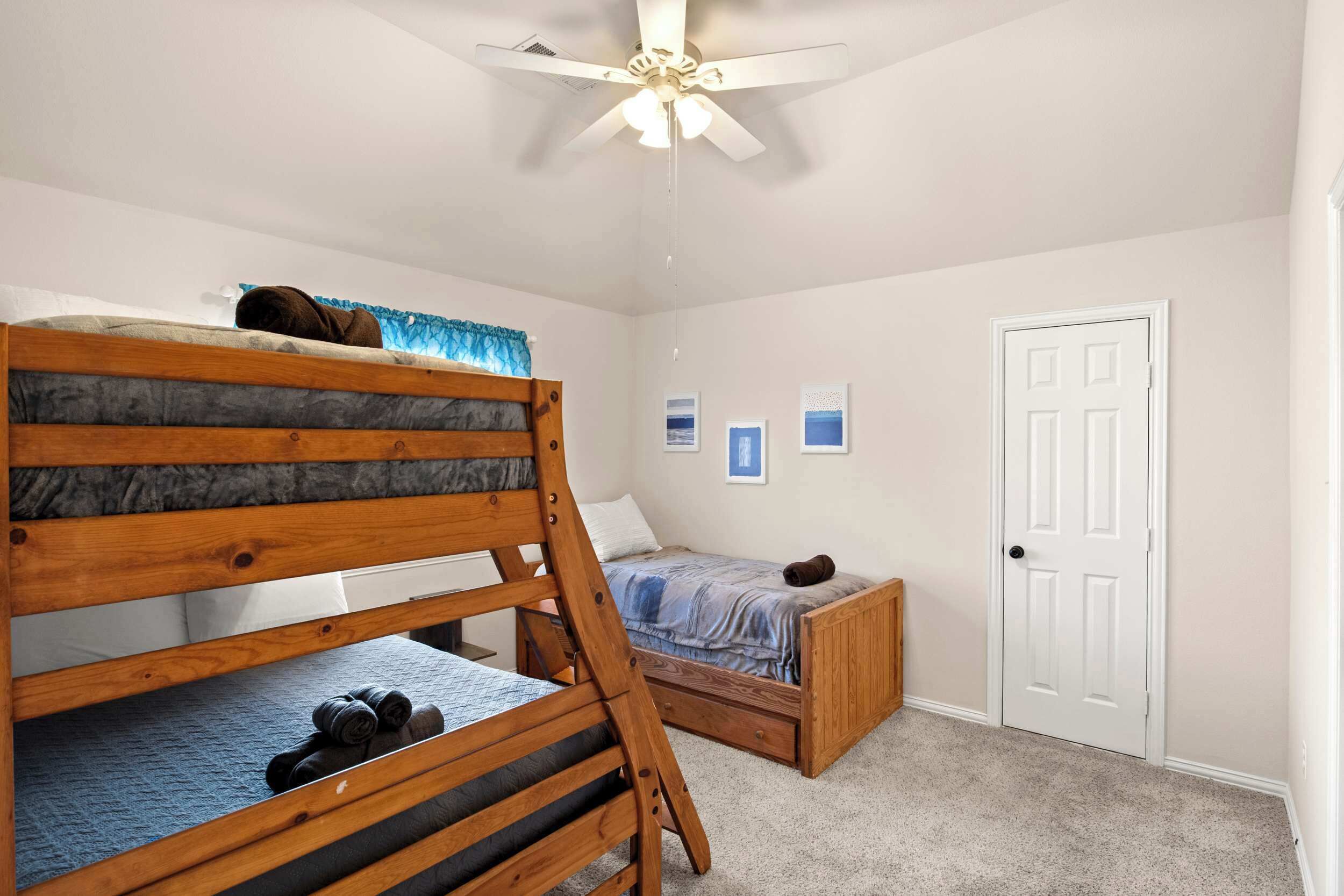 A bedroom with bunk beds, a ceiling fan, and a door.