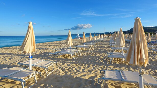 A beach with rows of sun loungers and umbrellas, a clear blue sky, and a calm sea. - Valtur Sardegna - Eos Costa Rei  (Costa Rei)