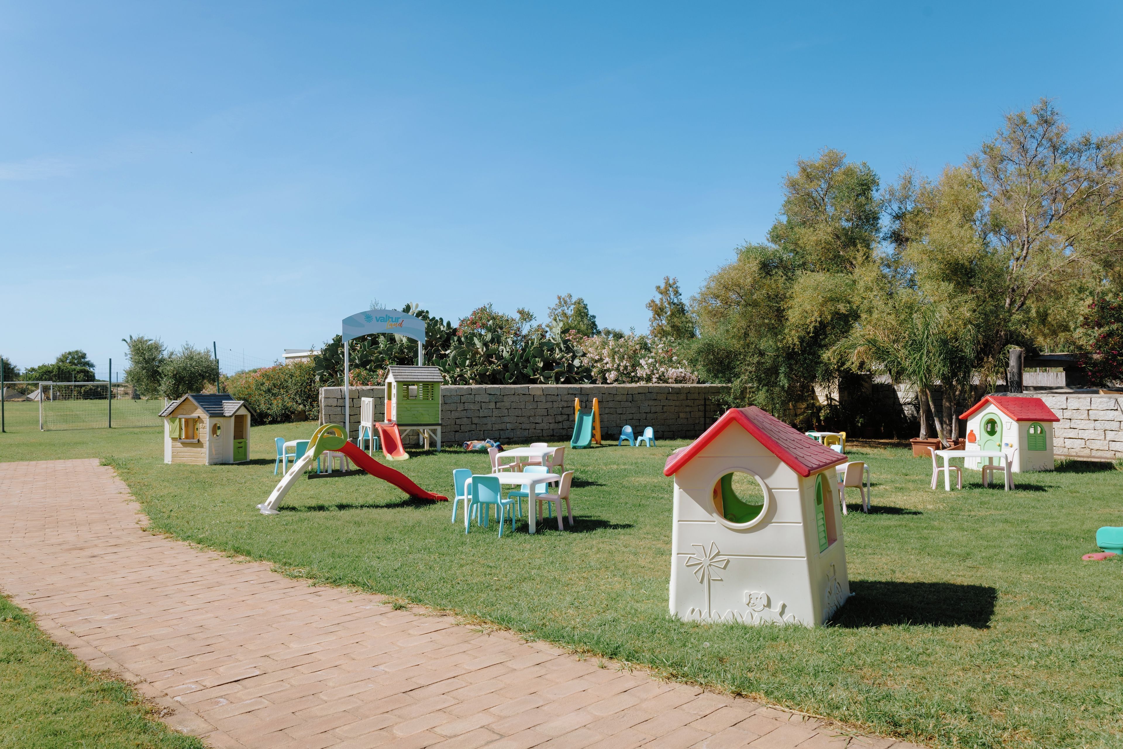 Ein Spielplatz mit Rutschen, Spielhäusern und einem Pflasterweg.
