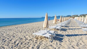 A beach with rows of sun loungers and umbrellas, a clear blue sky, and the sea in the background. - Valtur Sardegna - Eos Costa Rei  (Costa Rei)