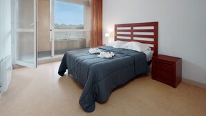 A bedroom with a bed, a nightstand, a window with curtains, and a sliding glass door leading to an outdoor area. - Charming Apart for 4 Near the Sea (Agde)