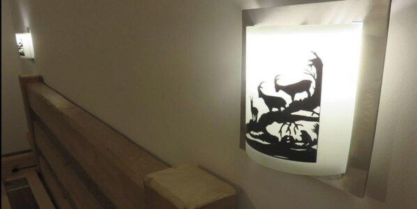 A hallway with a bench and a wall-mounted light fixture displaying a silhouette of animals. - Appartement mit Zwei Schlafzimmern in Grainau (Grainau)