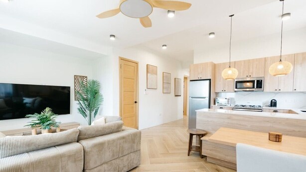 A modern kitchen with a built-in microwave, a refrigerator, and a dining area with a table and chairs. - Cinnamon Suite, Stylish 2BR | Central St George (Saint George's)