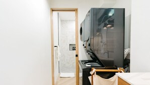 A modern bathroom with a large mirror, a black sink, and a wooden door leading to another room. - Cinnamon Suite, Stylish 2BR | Central St George (Saint George's)