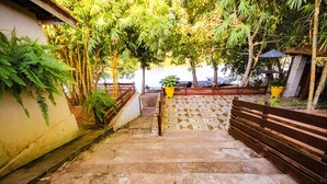 A set of concrete stairs leading up to a building, surrounded by lush greenery and a wooden fence. - Pesqueiro - rancho com lazer completo em Coxim/MS (Coxim)