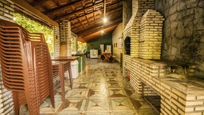 A rustic kitchen with a brick oven, wooden furniture, and a patterned floor. - Pesqueiro - rancho com lazer completo em Coxim/MS (Coxim)