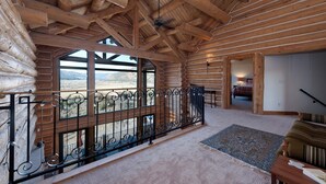 Ein Holzblockhaus-Interieur mit einem großen Fenster, das einen Blick auf die Berge bietet.
